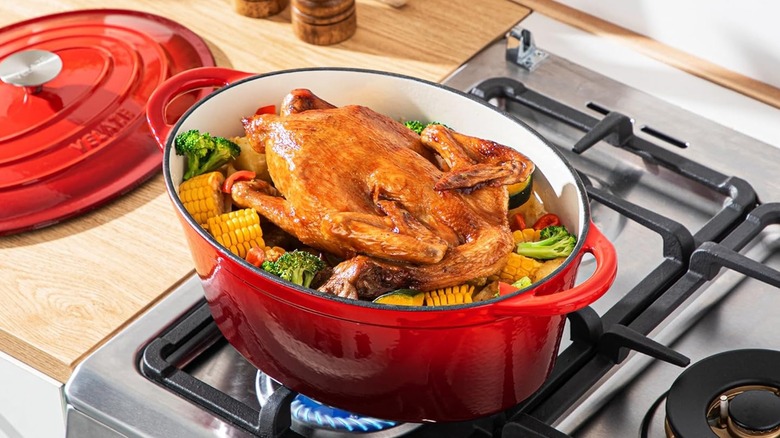 Red Dutch oven on a stove with a chicken inside