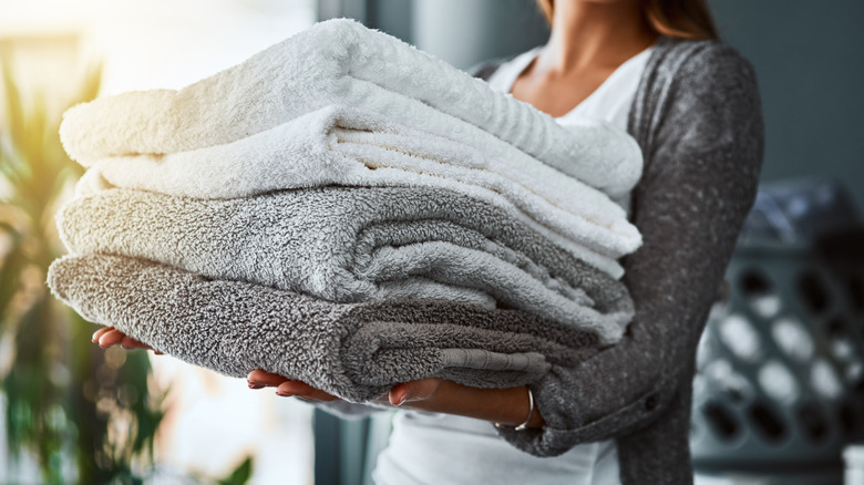 A woman carrying a stack of freshly washed towels
