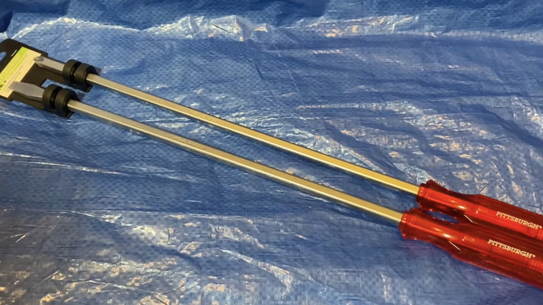 A pair of Pittsburgh long-reach screwdrivers with red handles placed on top of a blue propylene sack.