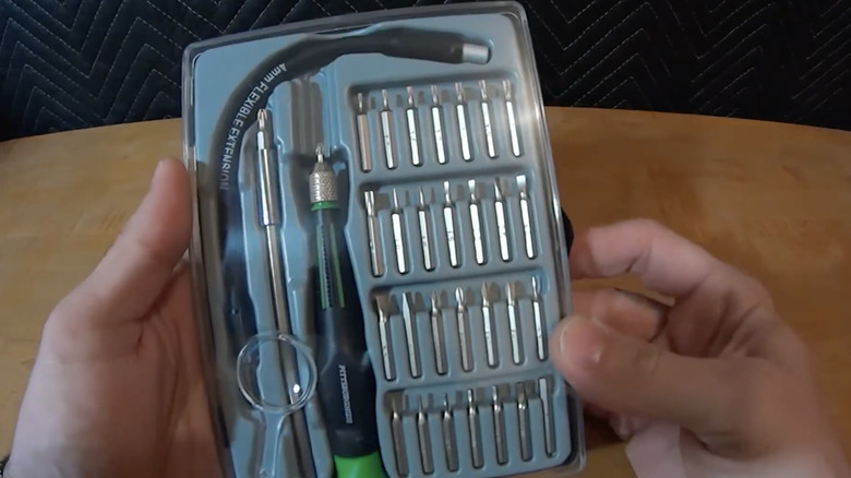Hands holding the Pittsburgh 34-piece screwdriver set with case over a wooden table.