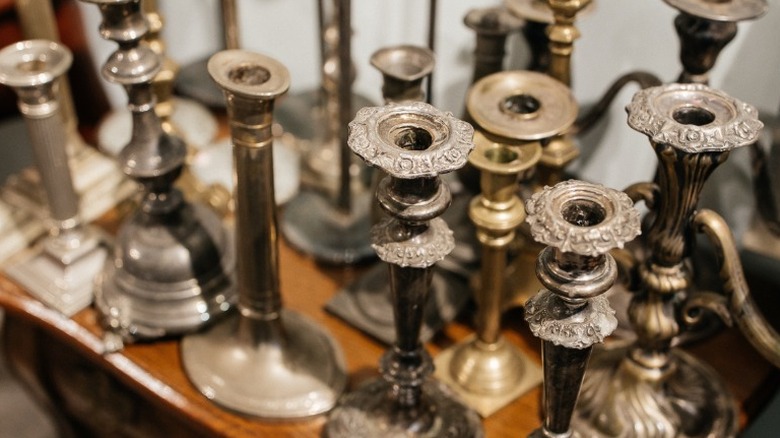 A collection of old silver candlestick holders on a tabletop.