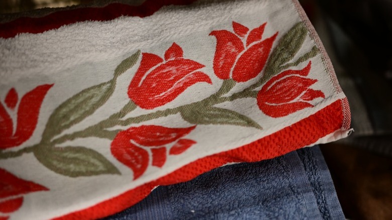 A white tablecloth featuring red tulips and green leaves.