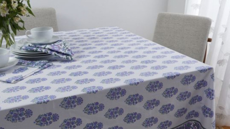 Purple and white floral tablecloth against gray chairs and wall