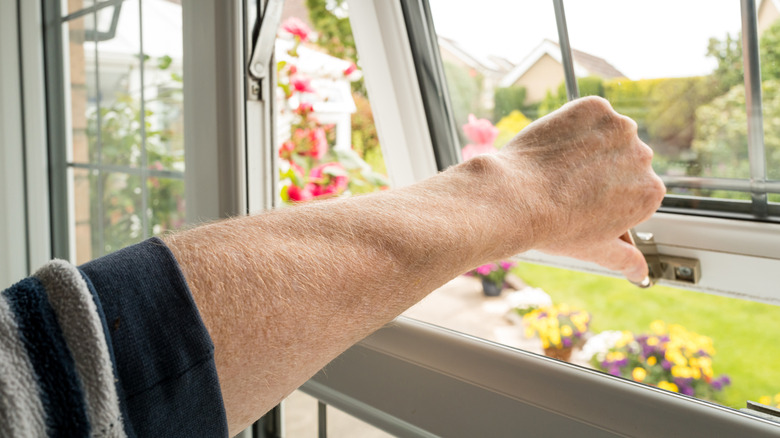 Person opening window in summer.