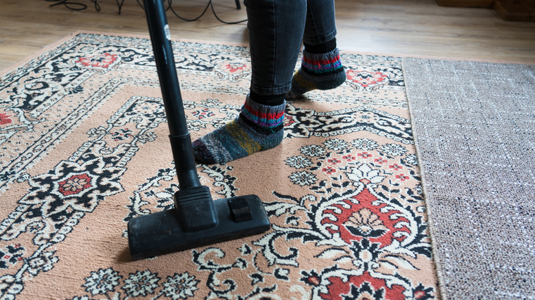 Person vacuuming rug.