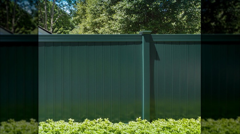 Vinyl privacy fence in yard with rocks near fence