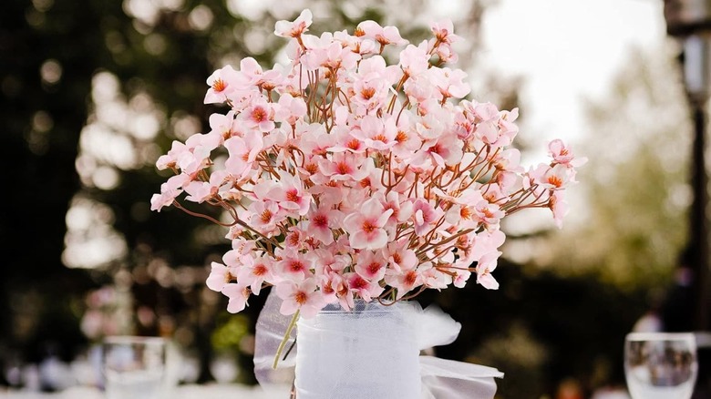 Cherry blossom stems with pink flowers in a ribbon covered vase