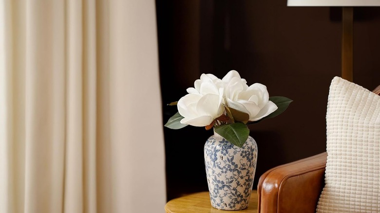 Faux magnolia flowers in a blue and white vase on a couch-side table