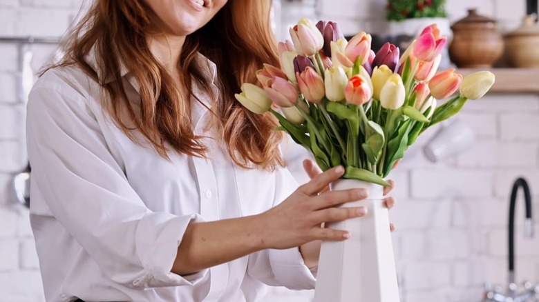 Woman looking at a vase full of artificial tulips
