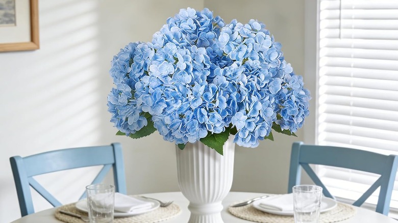 Blue hydrangeas in a white vase on a set kitchen table