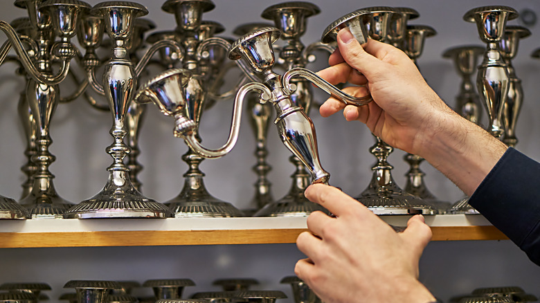 Person picking up a silver candlestick