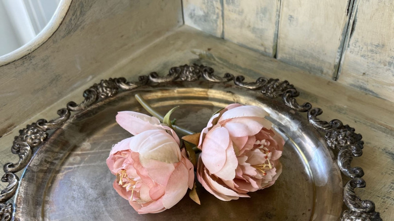 A tarnished silver tray with two flowers on top