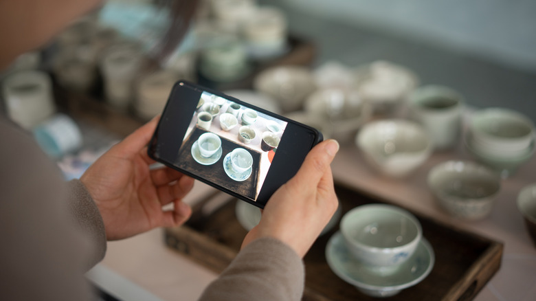 Woman taking photos of ceramic cups