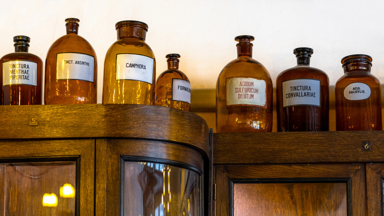Antique amber jars lined up on wooden cabinet