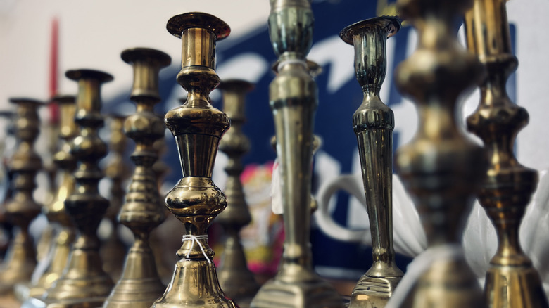 Rows of vintage brass candlesticks on shelf
