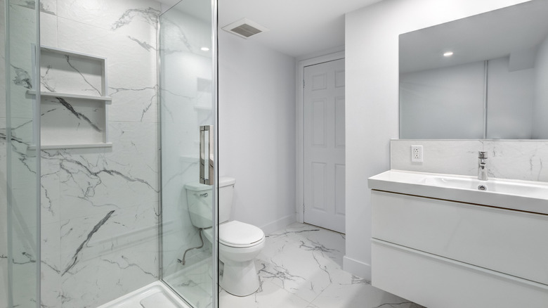 White bathroom with marble looking floors and shower