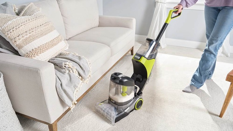 A person cleaning their living room carpet with Ryobi's 18V One+ HP Cordless SWIFTClean Rug and Carpet Cleaner
