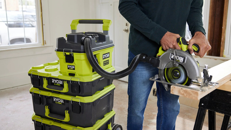 A shot showing Ryobi's 18V One+ LINK Cordless 3-gallon Wet/Dry Vacuum Kit plugged into the dust collection port of a Ryobi wood saw