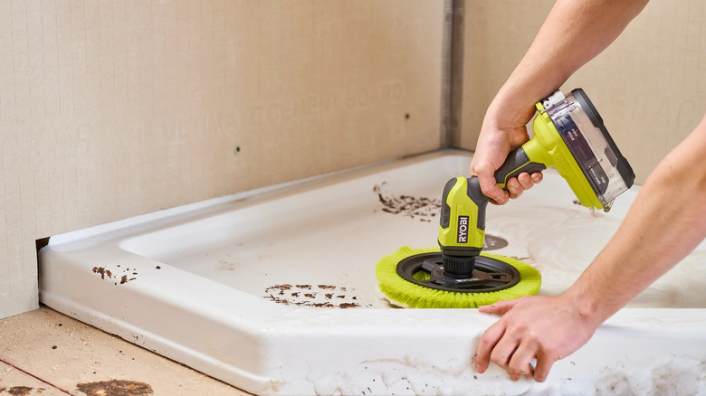 A person cleaning with a Ryobi scrubbing brush tool