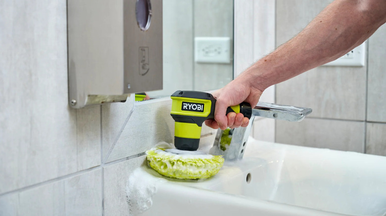 A person cleaning a sink with Ryobi's USB Lithium Compact Scrubber Kit