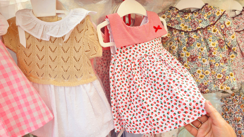A person holding the hem on a strawberry print children's dress.