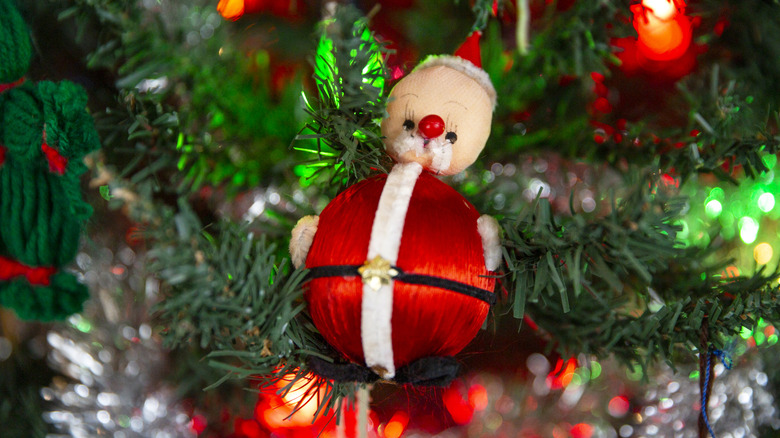 A vintage kitschy Santa ornament displayed on a tree.