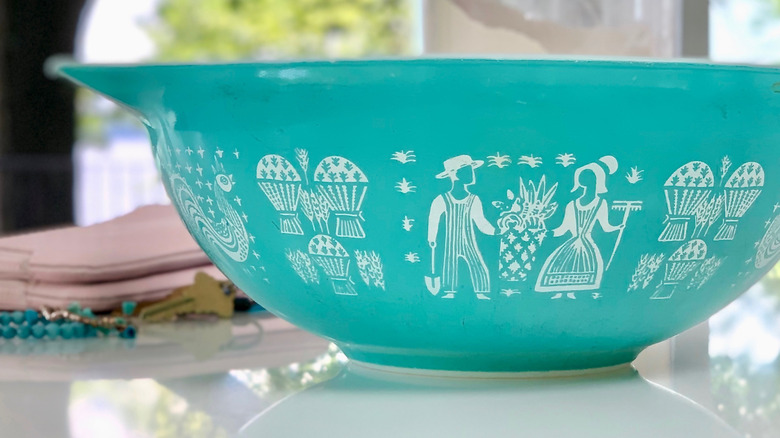 A teal vintage Pyrex bowl with a harvest pattern.
