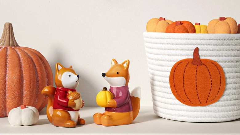 A few figurines for fall, including a fox holding a yellow pumpkin