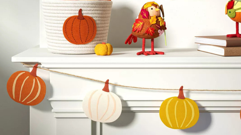 A closeup of a pumpkin garland hanging across a fireplace mantel