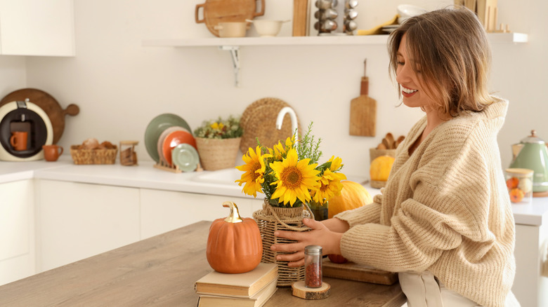 A woman placing fall decor on her kitchen counter