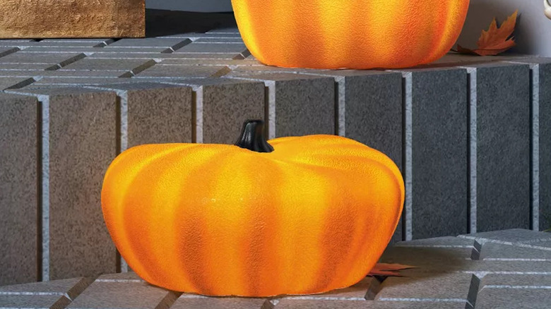 A lit up pumpkin figure on stone steps