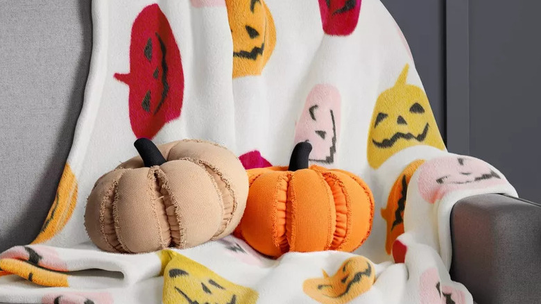 Two pumpkin shaped pillows sitting on a couch