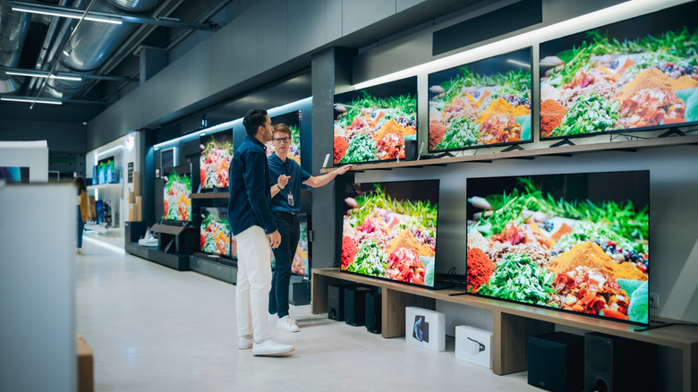 A man shopping for a TV and talking to a salesman