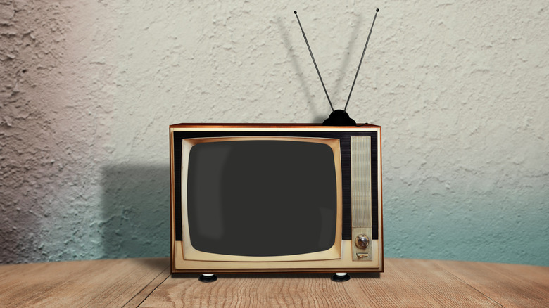 A retro TV with an antenna on a wooden table.