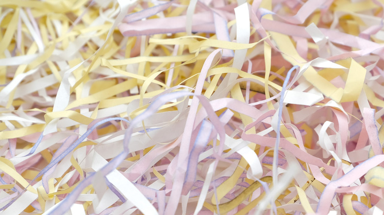 A pile of pale pink, yellow, and white shredded paper.