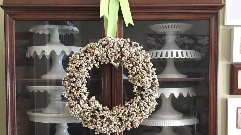 Faux berry wreath hanging on a kitchen cabinet