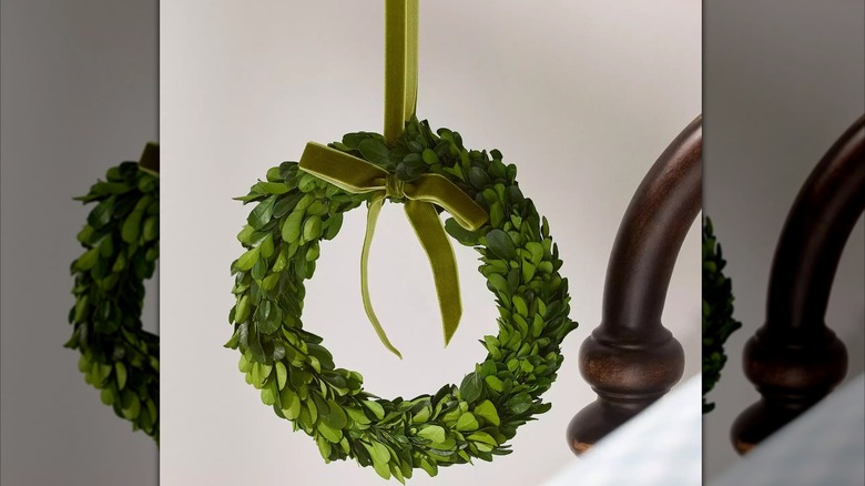 Faux boxwood wreath hanging by a velvet ribbon