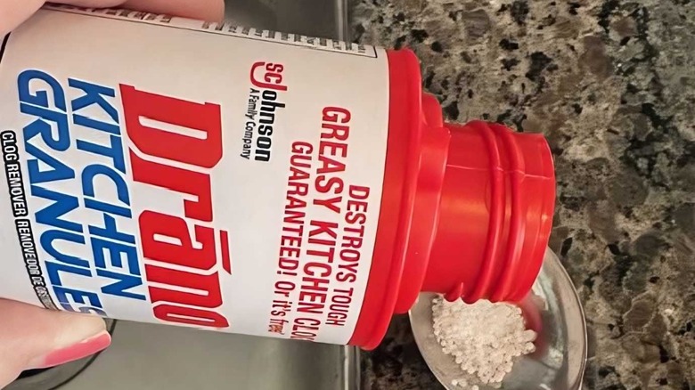 a person adding Drano Kitchen Granules Drain Clog Remover and Cleaner into a spoon