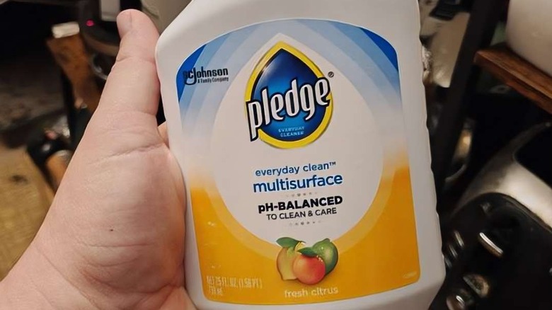 a person holding a bottle of Pledge pH Balanced Multi Surface Cleaner Spray
