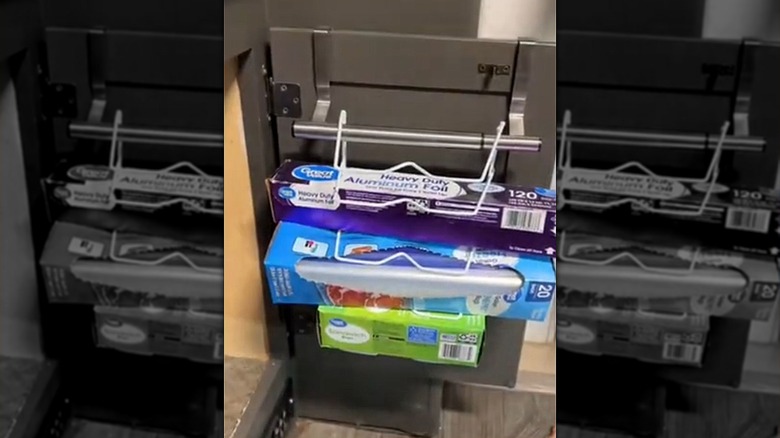An over-the-door towel rod on a cabinet door with a dish drying rack to store kitchen essentials