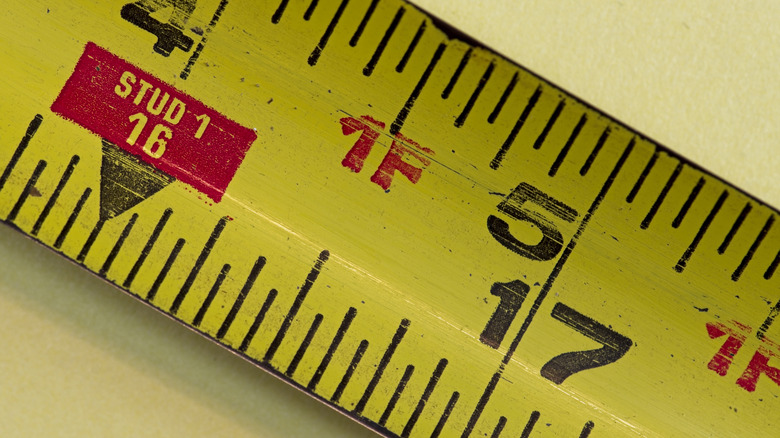 Close up of measuring tape numbers between 16 and 17 inches with 16 inches surrounded by a red box marked stud 1