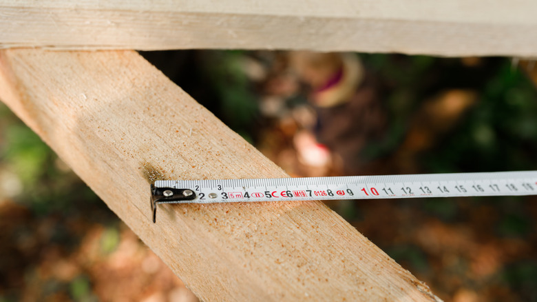 White tape measure at an angle up againt a diagonal wooden beam