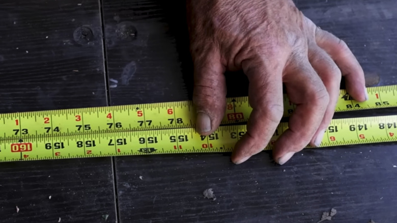 Two sides of a tape measure facing the opposite direction with a man's hand holding them close together