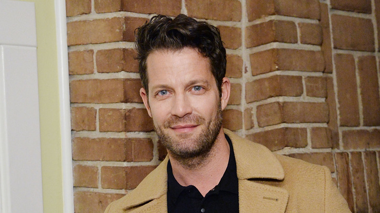 HGTV star Nate Berkus stands in front of a brick fireplace
