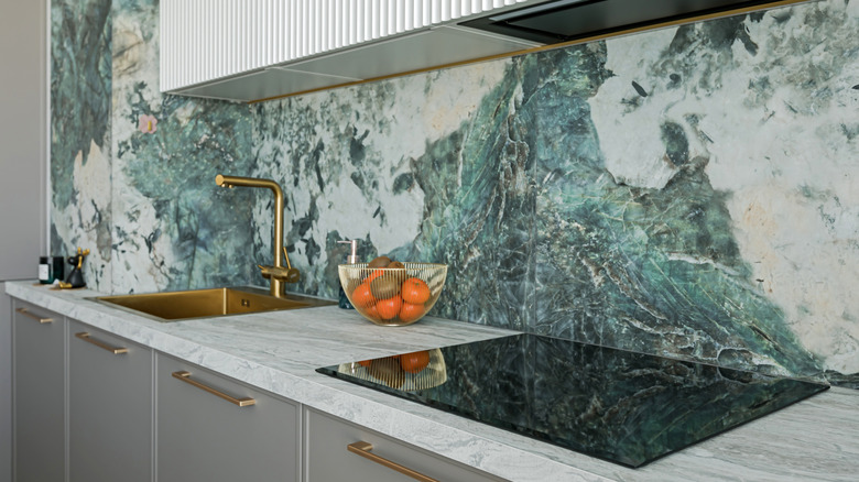 Bold green marble slabs are used as a backsplash in a modern kitchen