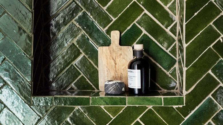 Racing green Zellige tiles are installed on a shower wall and niche
