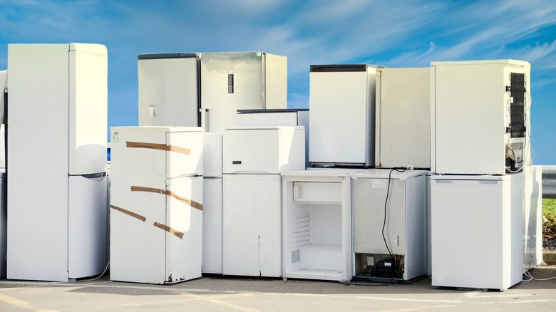 Old refrigerators stacked on pavement