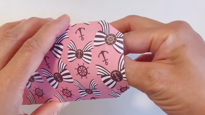 Hand holding a paper craft pouch made from wrapping paper