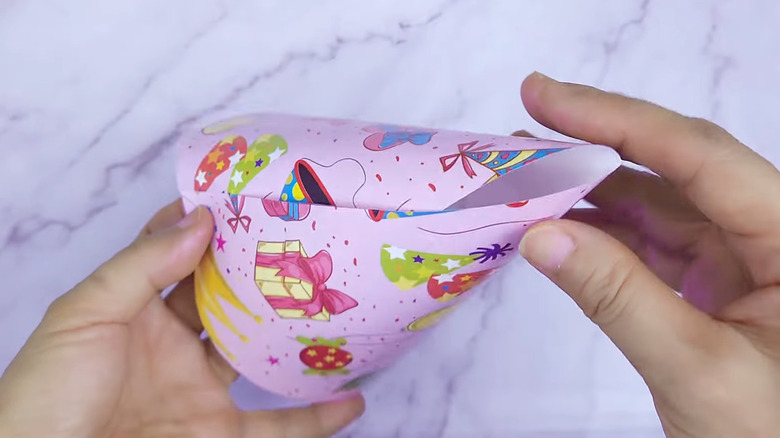 Person making party hat from wrapping paper