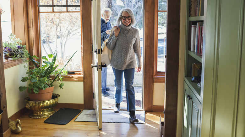 A woman walking through the front door of a home